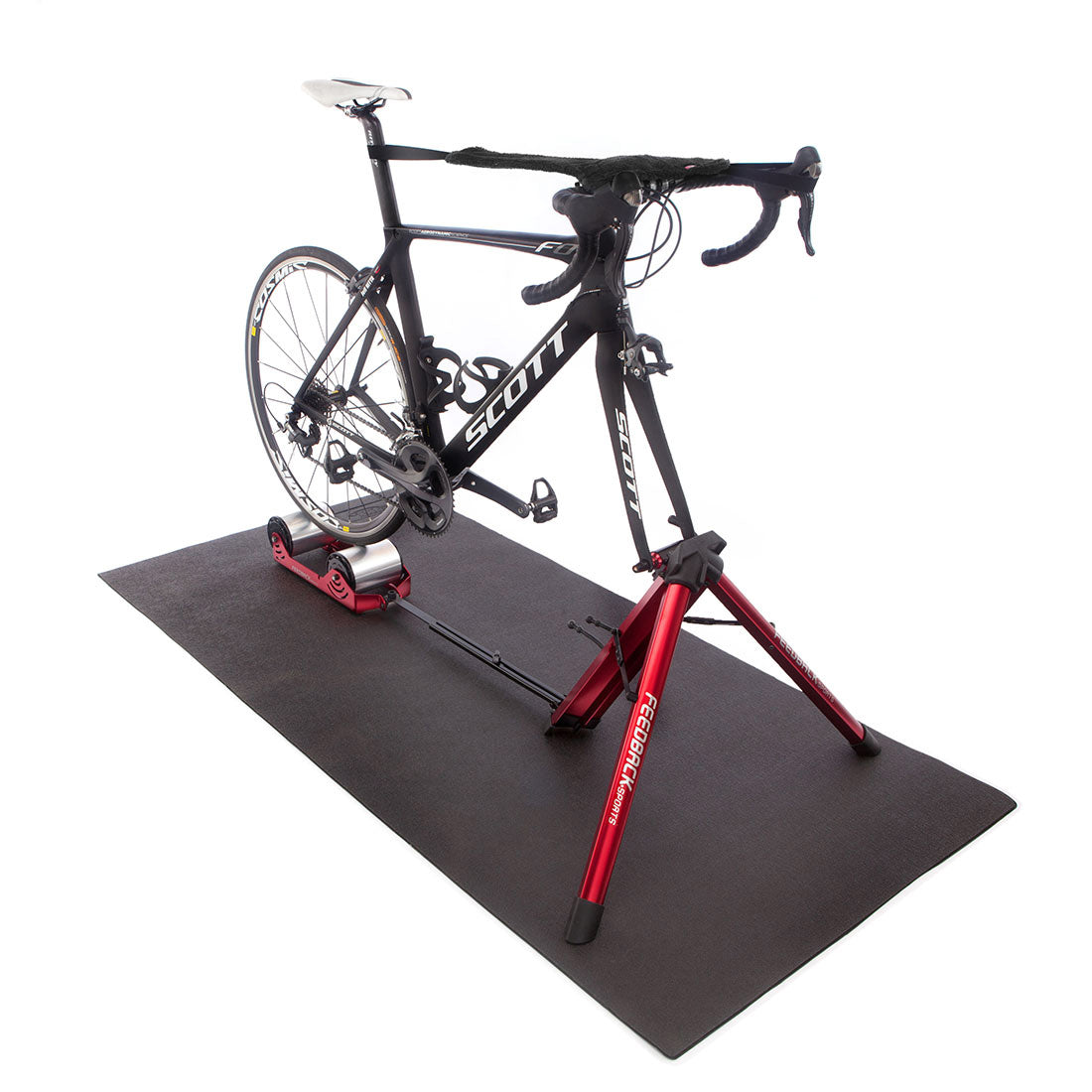 Feedback Sports Omnium bike trainer on trainer mat in studio with black bike installed.