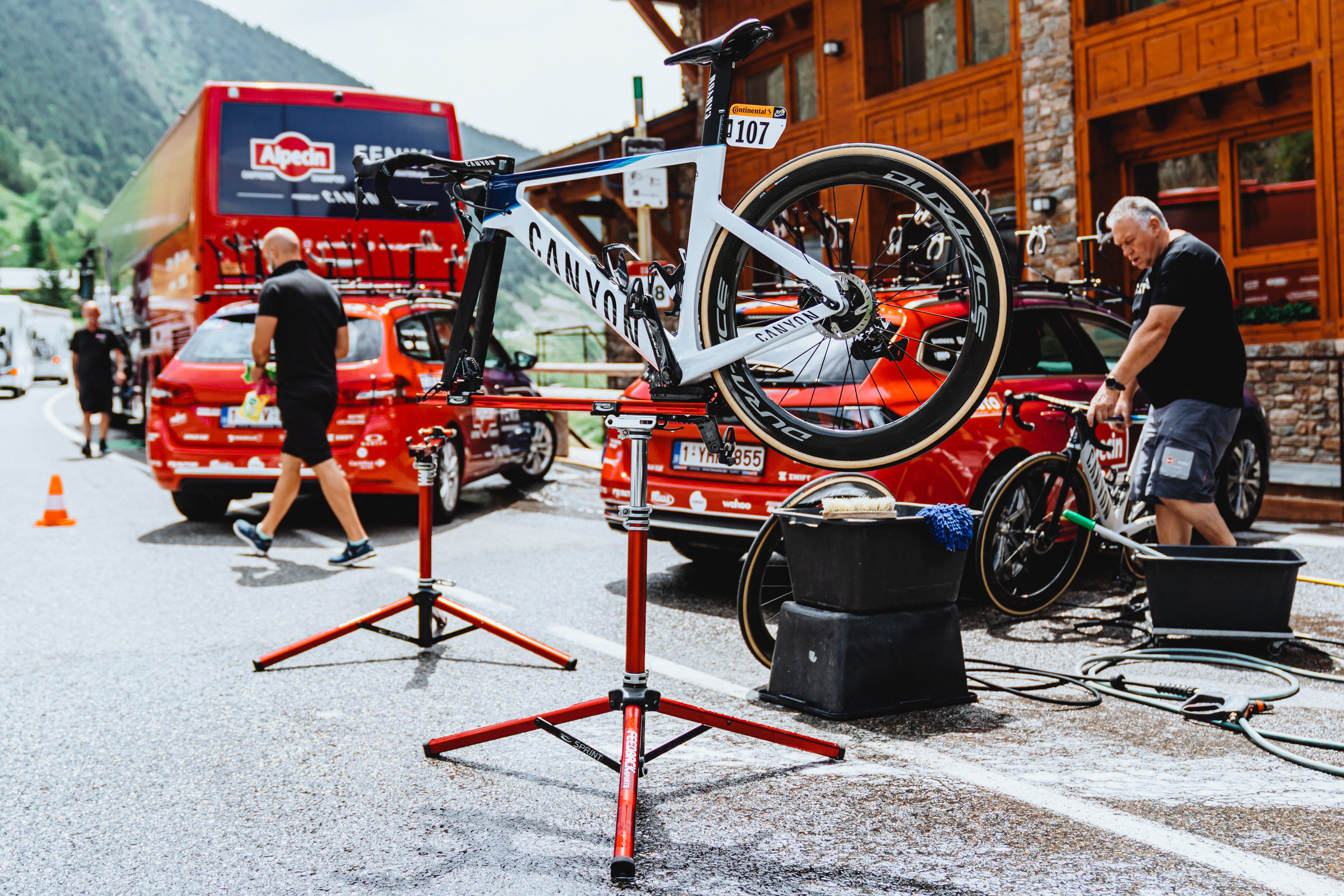 2 spring repair stands at the tour de france with a bike on one and the alpecin fenix team mechanics