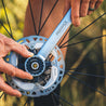 Close up of person installing bike disc brake rotor outdoors using lockring tool.