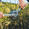 Close up of person removing bike cassette cogs on a bike wheel using cassette pliers and lockring tools outdoors.