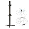 Feedback Sports Velo Cache vertical bike storage stand in studio on white not in use. next to one in use with ghosted bikes.
