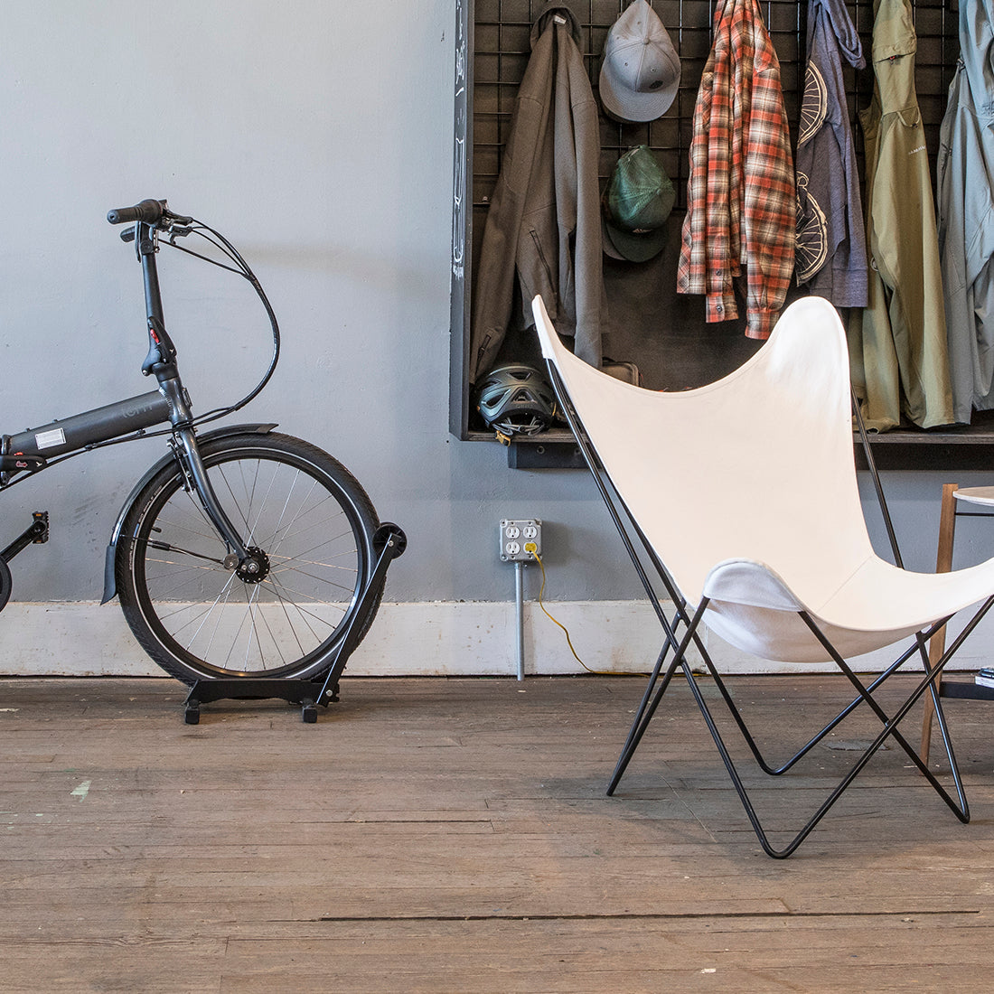 Small apartment with chair and coat rack with bike in free standing storage system.