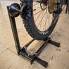 Rear view close up of mountain bike being installed into RAKK XL bike storage stand indoors.