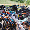 Large assortment of mountain bikes on A-Frame bike storage rack outdoors.