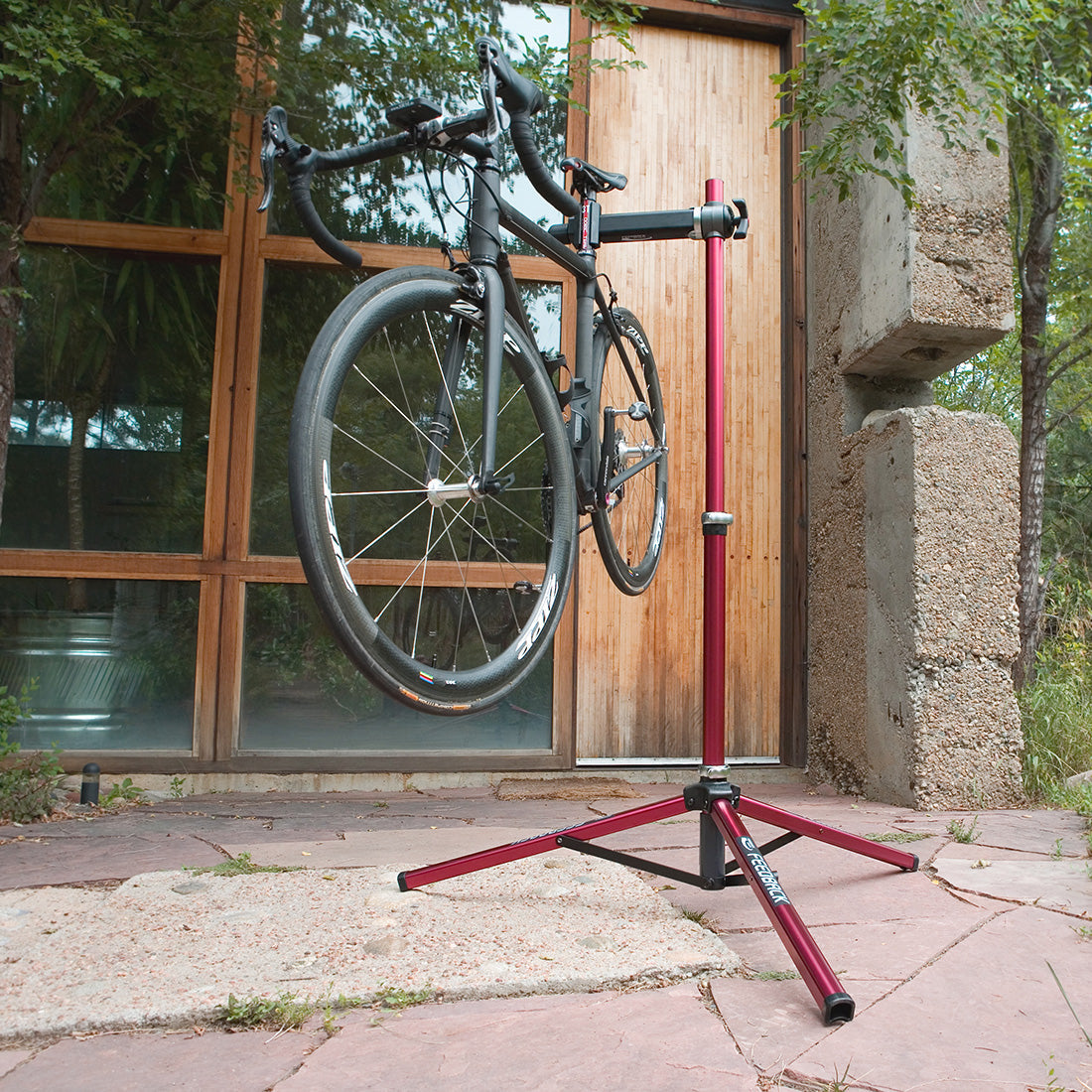 Feedback sports Ultralight bike repair stand deployed and holding a bike in front of a building.