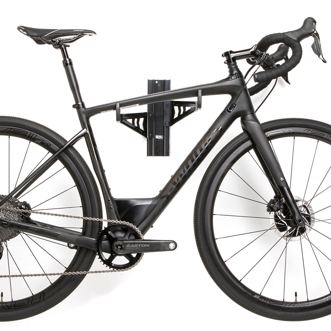 Black road bike viewed from side, suspended on wall mounted bike storage cradle arms.