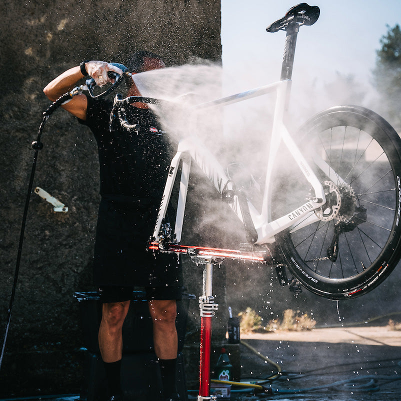 Bike mechanic working outdoors washing a bike in a Sprint repair stand.
