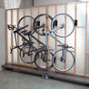 Three bikes suspended from Velo Hinge bike hooks on stud frame interior wall, bikes folded to lay flat against wall.