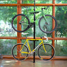 Feedback Sports Velo Column vertical bike storage stand in use with two bikes in front of a wall of windows.