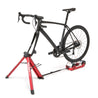 Black road bike mounted on Omnium stationary bike trainer in studio setting.
