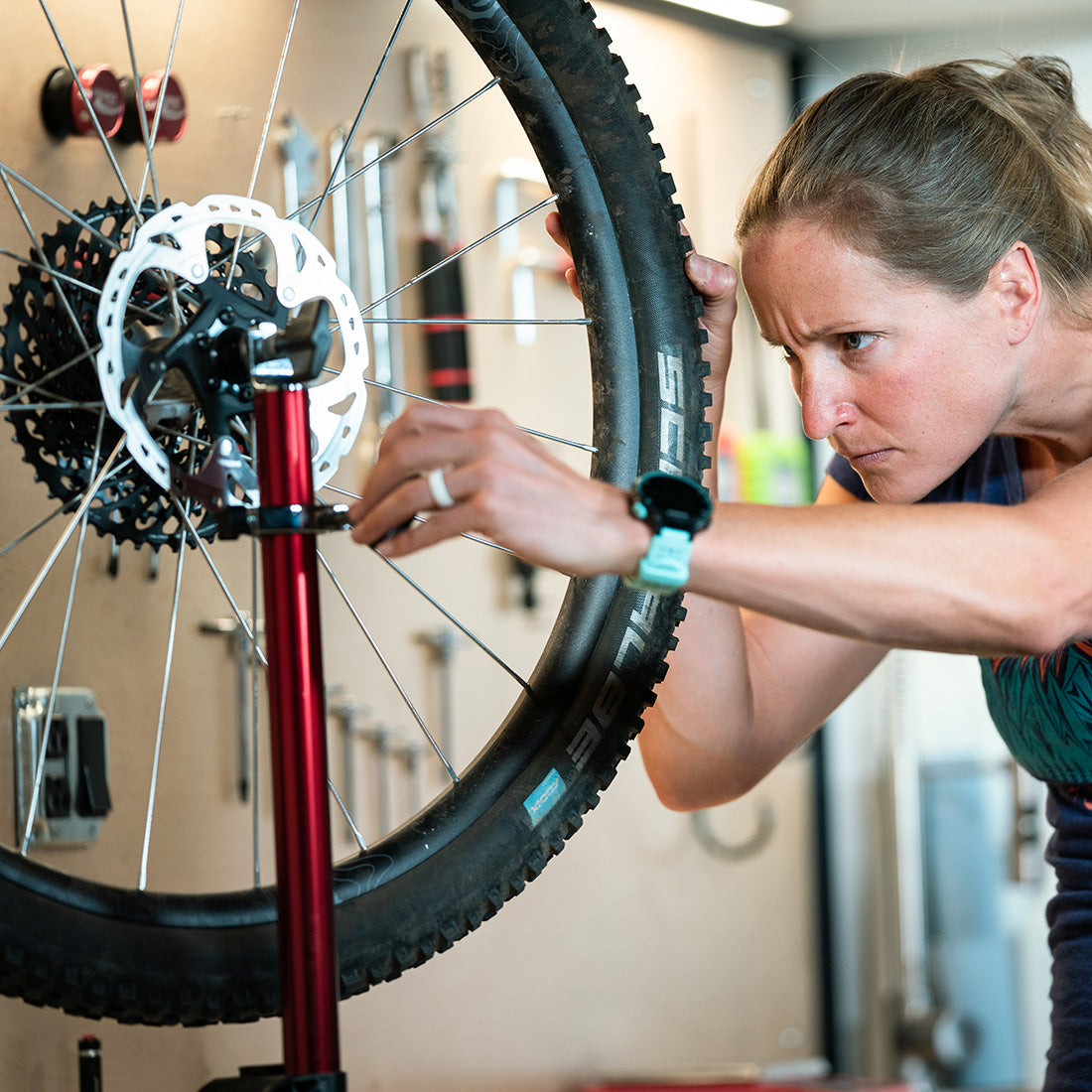 Person inspecting bike wheel with wheel in truing stand in a bike shop.