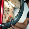 Close up of person using spoke wrench to tighten bike wheel spoke.