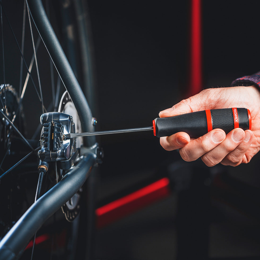 Person using screwdriver on bike in close up with dark background.