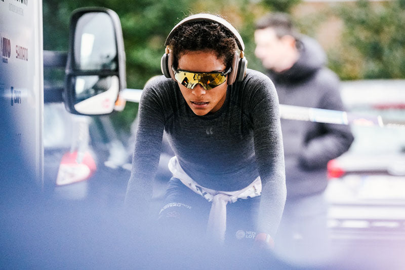 Woman with headphones warming up for bike race.