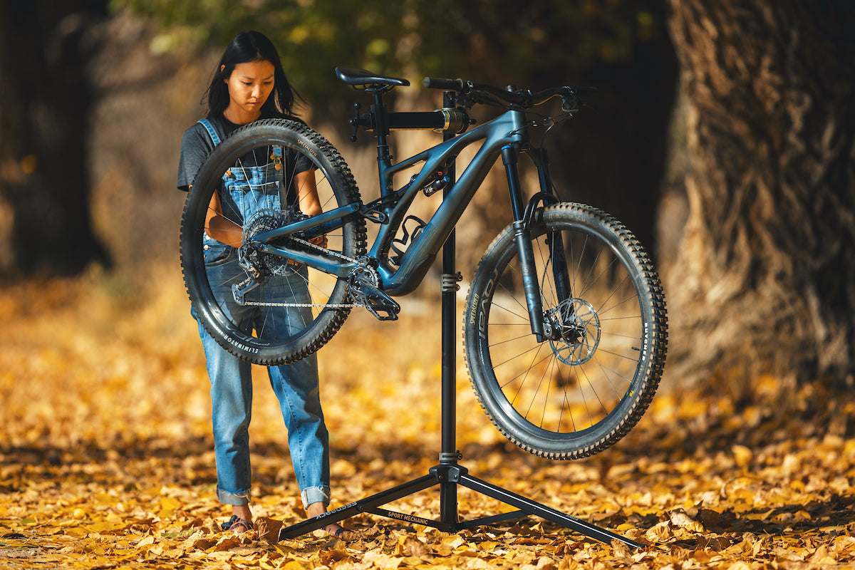 woman working on bike outside using the sport mechanic repair stand