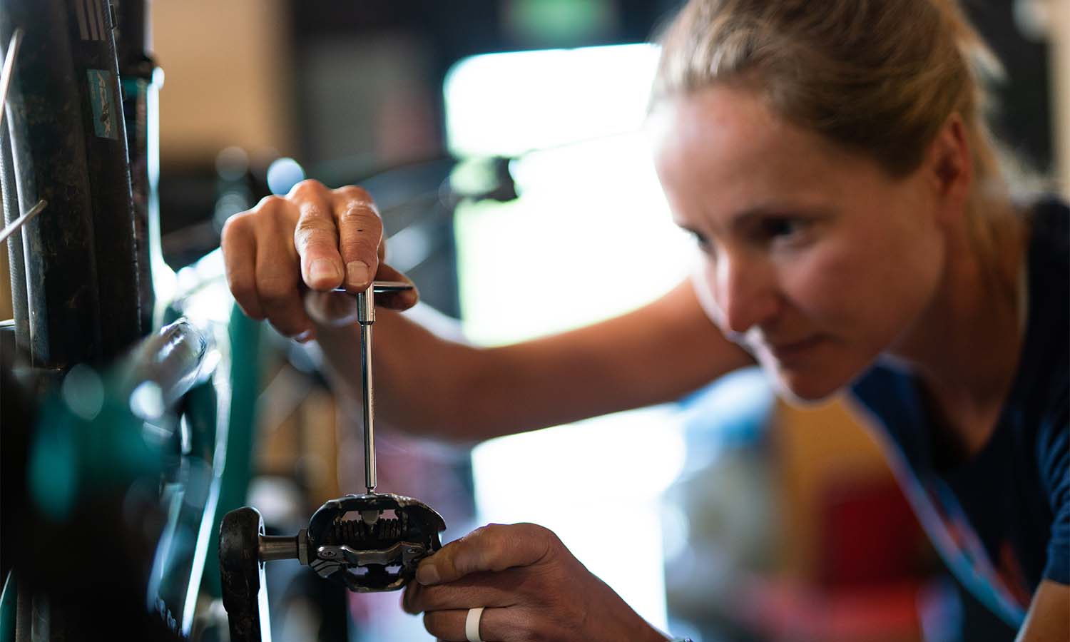 woman fixing a bike pedal with a hex wrench.