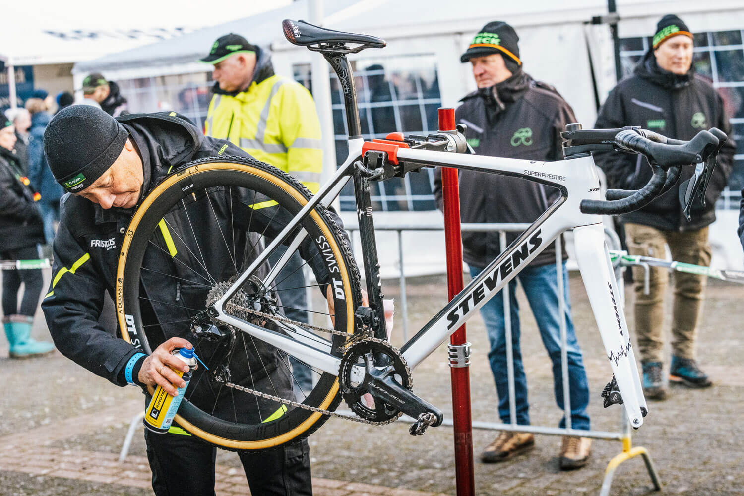 Man working on cyclocross bicycle outdoors at event.