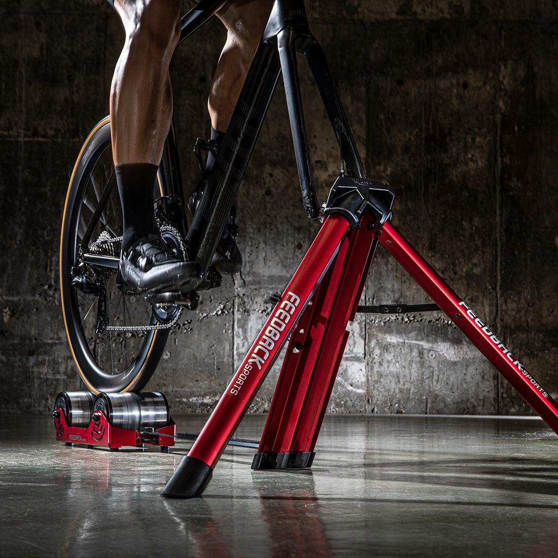 Close up of Omnium bike trainer front tripod in use in dark studio setting.