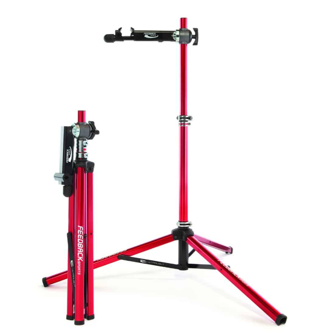 feedback ultralight bike repair stand open and set up next to another feedback ultralight bike repair stand folded up into it's most compact form